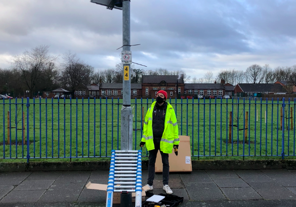 A white person standing in high-vis next to a lamppost, after installing EarthSense air-quality sensors