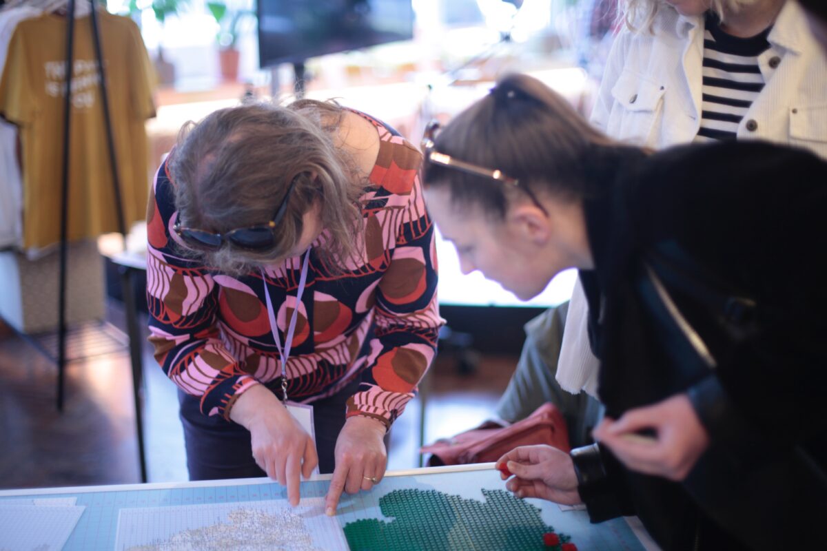 Sophie from Open Data Manchester helping another woman place her lego brick on the Happiness Index lego map