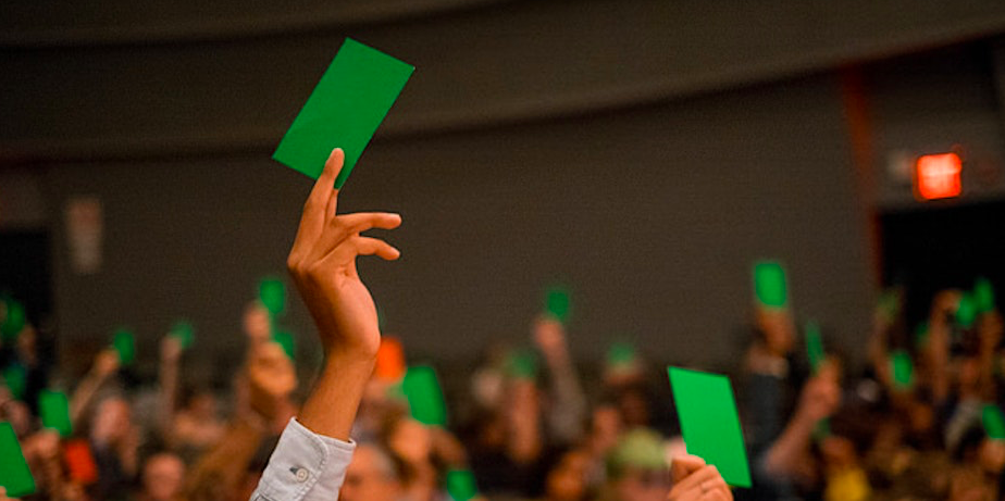 Hands with green cards in them being held up in a room